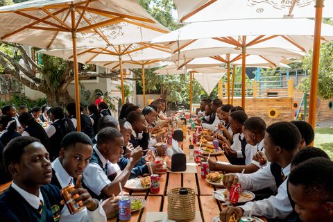 Learners and staff gathered along a restaurant table on a school outing