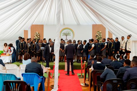 Uniformed learners performing at prize giving with the school logo behind them