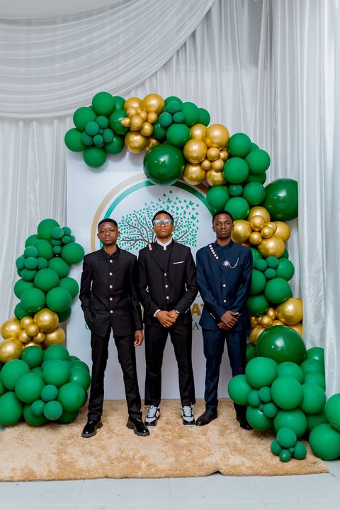 A group of prom guests in front of the Firm Foundation school crest