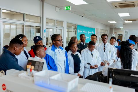Learners in laboratory coats watching a demonstration during the CIMAS visit