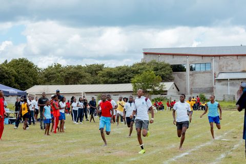 Learners racing on the sports field with school buildings in the background