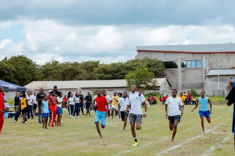 Learners racing on the sports field with school buildings in the background